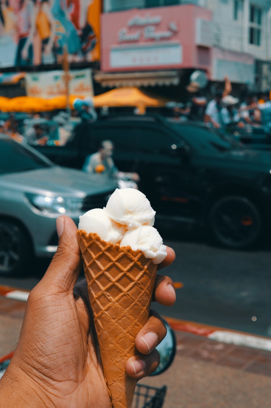 Ice cream cone held up on a busy street